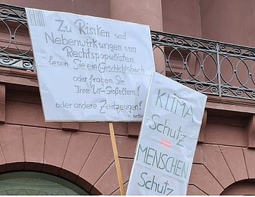 Auf Plakaten werden Klimaschutz und Schutz der Demokratie gefordert.